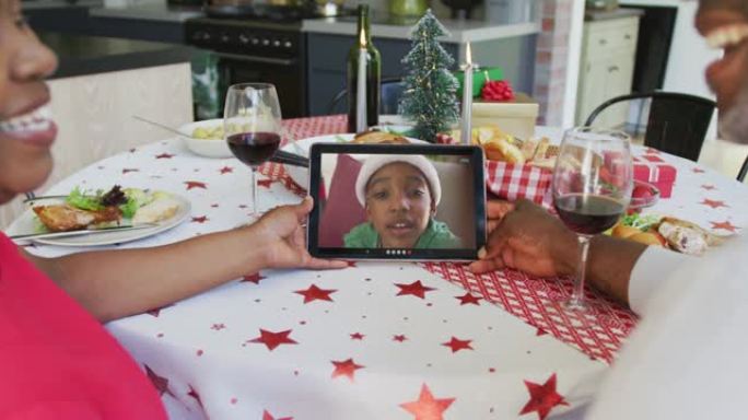 微笑的非洲裔美国夫妇使用平板电脑与屏幕上的男孩进行圣诞节视频通话