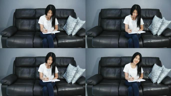 亚洲女性在沙发上写作和看书