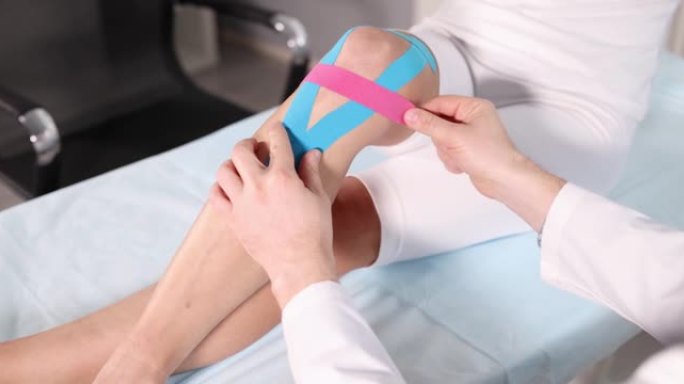 创伤学家将kinesio胶带粘在患者膝关节4k电影上