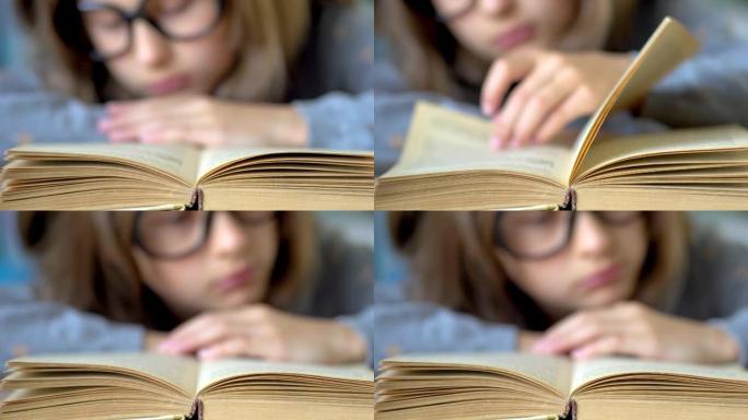 前景是一本书。一个戴着大黑眼镜的女孩正在看书。关闭视图。