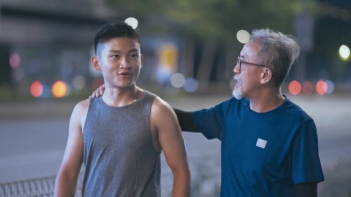 亚洲华裔活跃老人和他的儿子一起跑步运动后晚上在城市说话