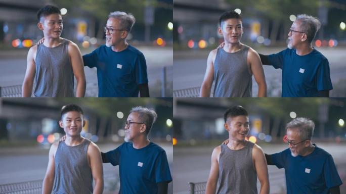 亚洲华裔活跃老人和他的儿子一起跑步运动后晚上在城市说话
