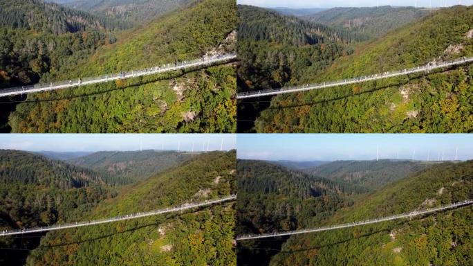 视频来自一架无人机，用钢绳飞过一座悬吊的木桥，飞越西德一片茂密的森林，可见的游客在桥上行走。