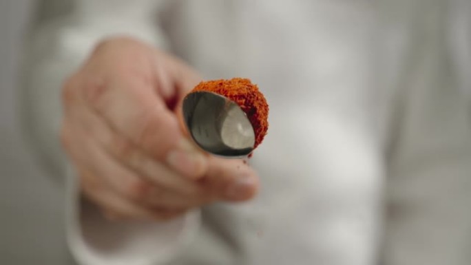 慢动作: 厨师用勺子撒红辣椒粉