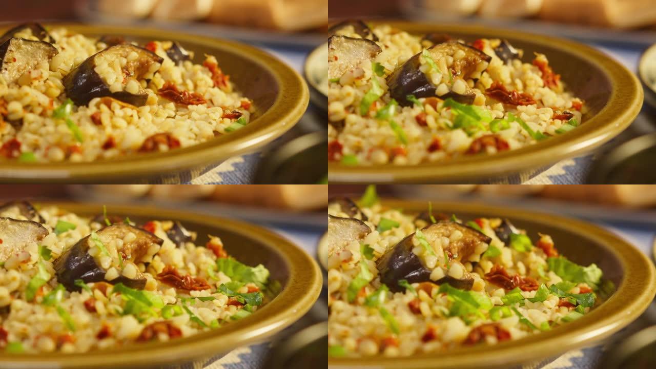 用茄子特写在碾碎小麦上撒上绿色植物。传统中东文化。美味的米饭和肉。阿拉伯美食。自制食品概念