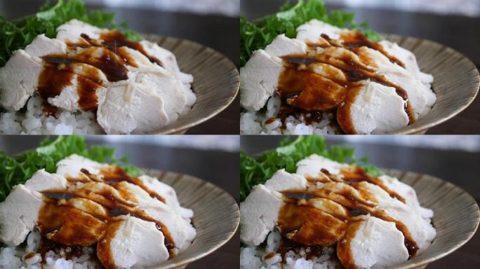 海南鸡饭视频。一盘撒上酱汁的蒸鸡肉。
