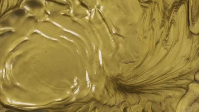 慢动作。波浪形金色抽象液体背景。风流吹走金漆。金色质地。液体黄金抽象背景。美丽的金属黄色纹理。金色波