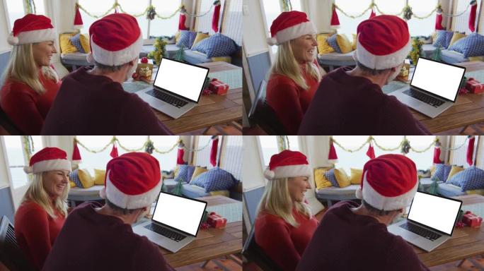 戴着圣诞老人帽子的白人夫妇在笔记本电脑上进行圣诞节视频通话，在屏幕上复制空间