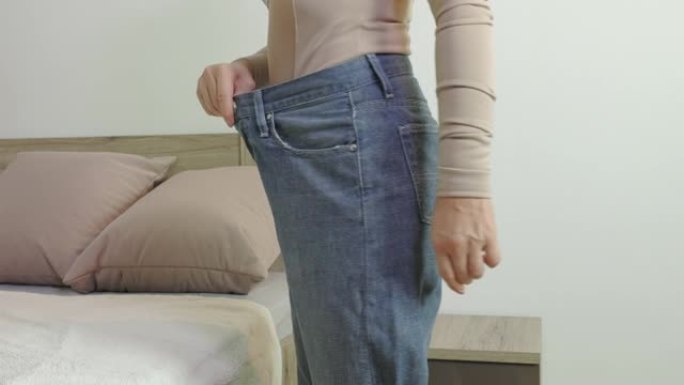 穿着超大牛仔裤的女人。饮食和减肥概念