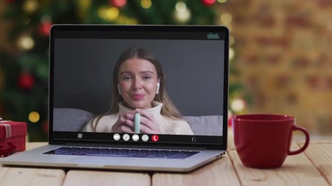 快乐的白人妇女在笔记本电脑上进行视频通话，带有圣诞节装饰和树木
