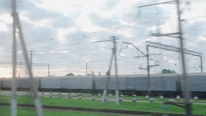 从高速火车的窗户看，在夏天背景下美丽的多云蓝天上，老生锈的棚车和高砖烟囱的景观。运输、旅行、铁路、道