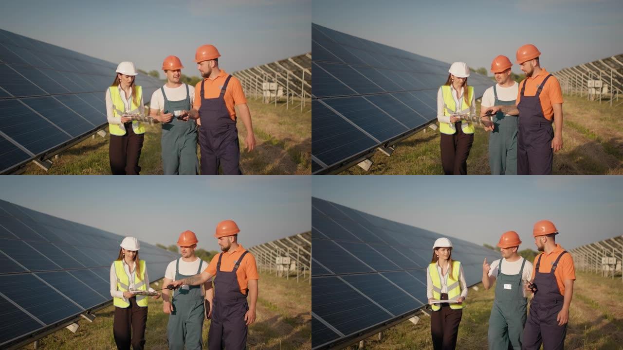 多样化的工程师在户外检查光伏电站上的太阳能电池板。几个工人合作控制清晰的电力能源生产。太阳能电池板领