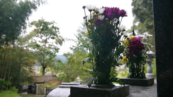 日本坟墓上的花，香烛散发出微弱的烟雾。