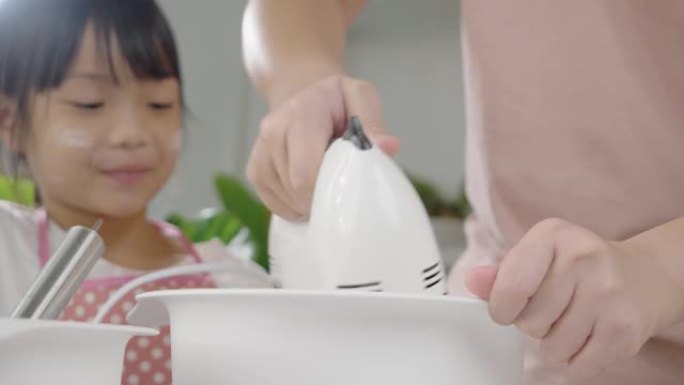 亚洲女孩在家里寻找如何与姐姐一起混合面团制作自制饼干的生活方式概念。