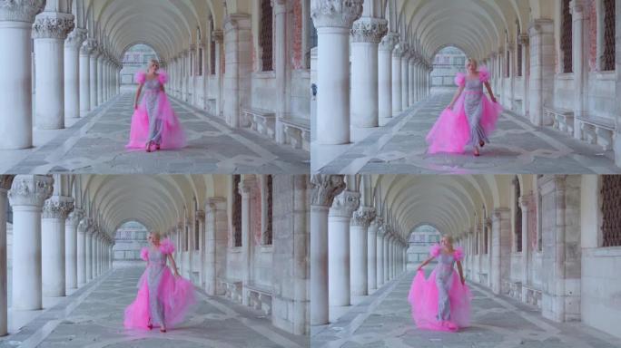 穿着粉红色连衣裙的女孩走在威尼斯的拱廊下