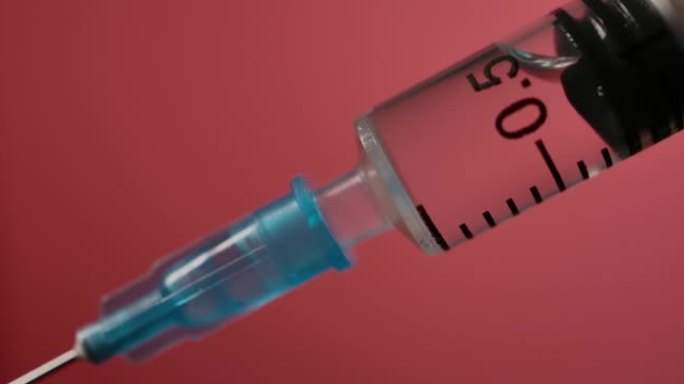 注射器中的注射液体在红色背景下的特写。药物药物针头注射器药物，流感疫苗小瓶剂量皮下注射治疗疾病预防预