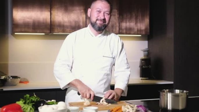 微笑的厨师用锋利的刀子切新鲜的蘑菇，做美味的菜