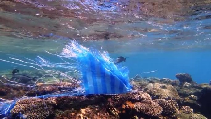 海里的垃圾。海洋的塑料污染。用过的蓝色塑料袋在阳光下慢慢漂流在水下。背光。塑料垃圾环境污染问题