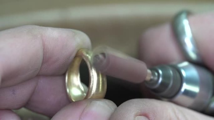珠宝商使用旋转工具抛光他创造的戒指。宏观，特写