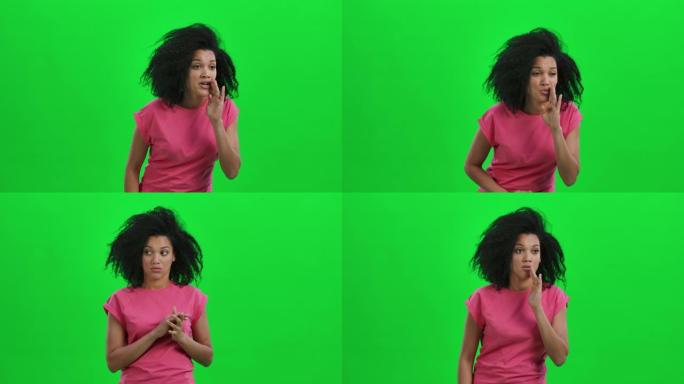 年轻女性非裔美国人的肖像用手遮住了嘴，低声说出了秘密，做出了安静的手势。黑人妇女在绿色屏幕上摆姿势。