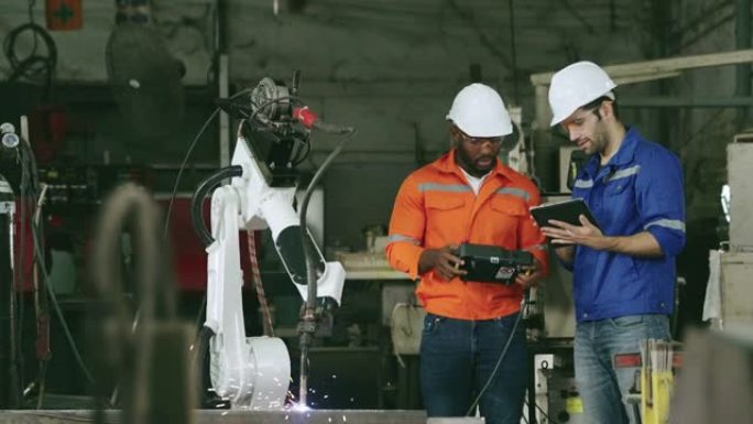 两名工程师在工厂工作控制自动化机器人。