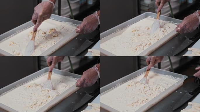 一名男子将马苏里拉奶酪与锅铲混合在一桶液体中