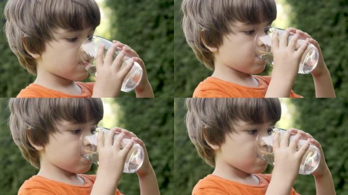 口渴的孩子在户外用玻璃喝水，阳光普照。小童水杯新鲜透明纯过滤水慢动作小童水杯水健康身体护理健康生活方