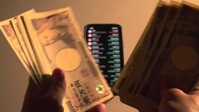 男人的手兴奋地握着一大笔钱。商人数日元钞票。显示市场价格的智能手机。
