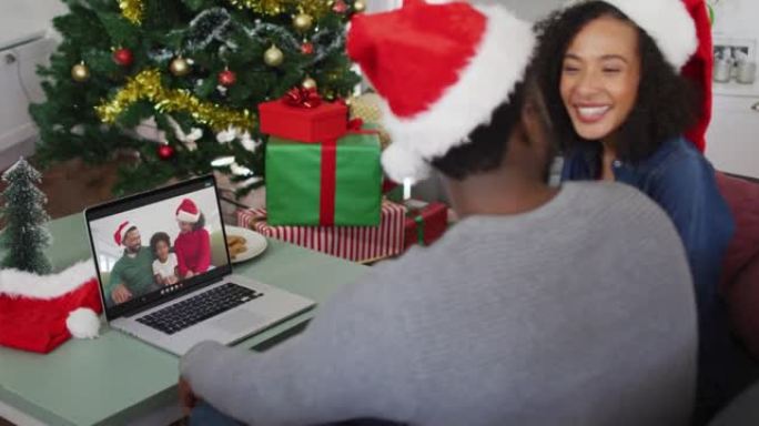 圣诞节期间，戴着圣诞老人帽子的非洲裔美国夫妇在家里的笔记本电脑上进行录像