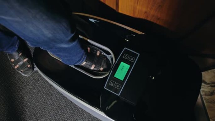 自动热收缩鞋套覆膜机。特写。机器自动将鞋套涂在病人的鞋子上。