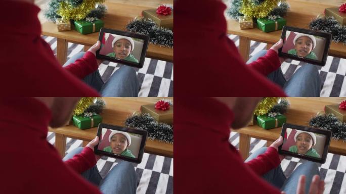白人男子使用平板电脑并在屏幕上与微笑的男孩一起挥舞圣诞节视频通话