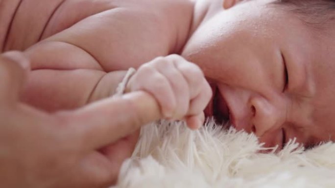 新生儿躺在床上。婴儿握着大人手指出生成长