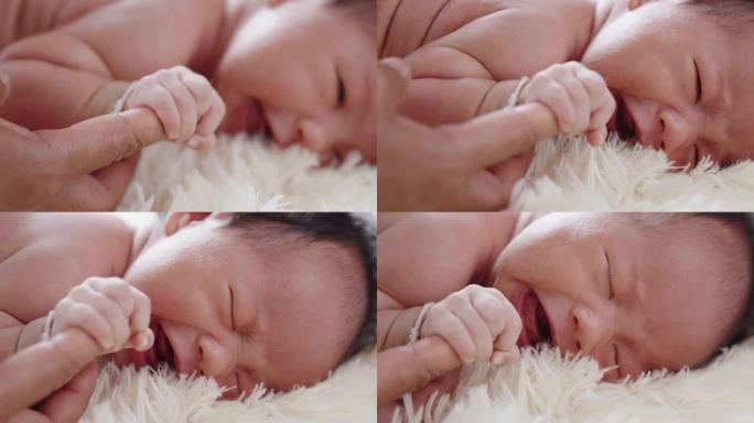 新生儿躺在床上。婴儿握着大人手指出生成长