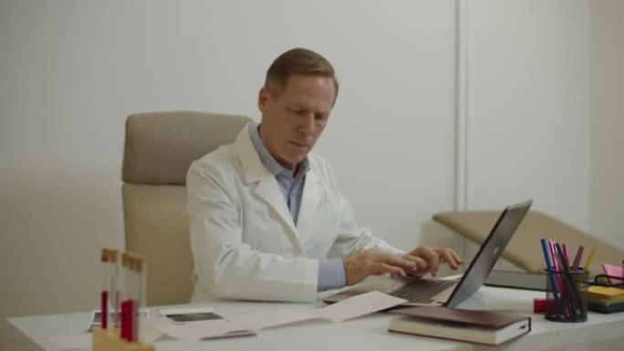 自信的男医生检查病人的心电图，并在笔记本电脑上输入心电图检查结果
