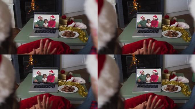 圣诞节期间戴着圣诞老人帽子的高加索夫妇的后视图在笔记本电脑上观看视频
