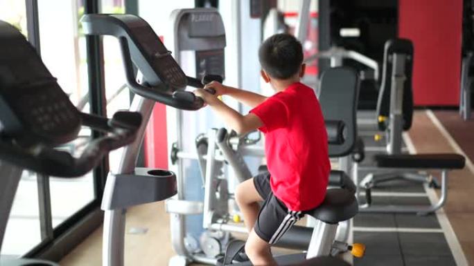 亚洲男孩在健身房用拳击和自行车锻炼微笑