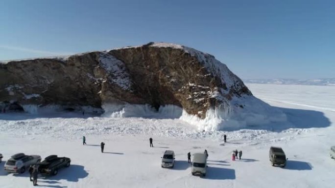 鸟瞰冰冻的贝加尔湖的岩石岛，许多人四处走动。受欢迎的旅游目的地。冬季景观。全景