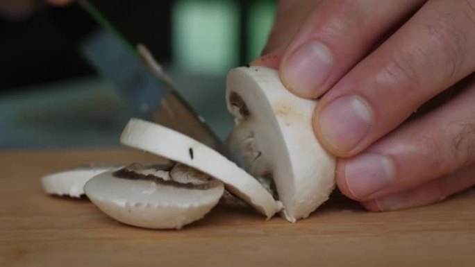 特写男子在木制切割板上切割香槟。饮食健康饮食。用刀在木板上切割香菇的雄性手。素食健康食品。饮食健康的