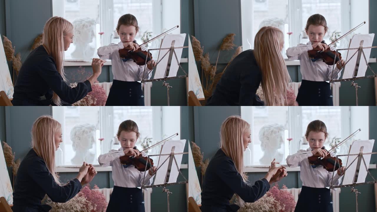 年轻的金发女老师教小女孩如何在拉小提琴时正确握弓
