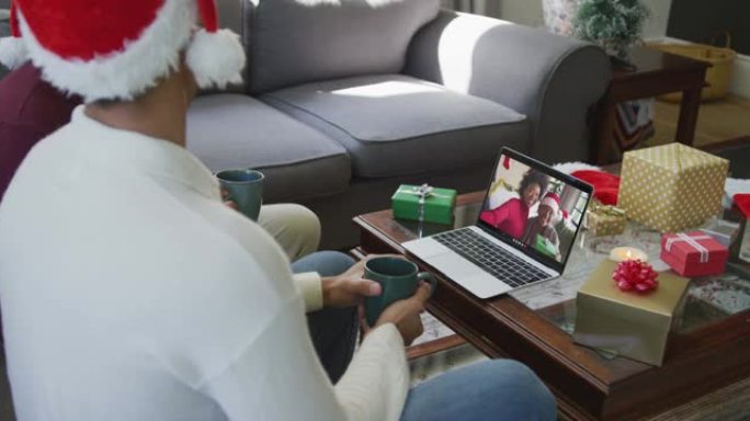混血儿的父亲和儿子使用笔记本电脑进行圣诞节视频通话，屏幕上有微笑的家人