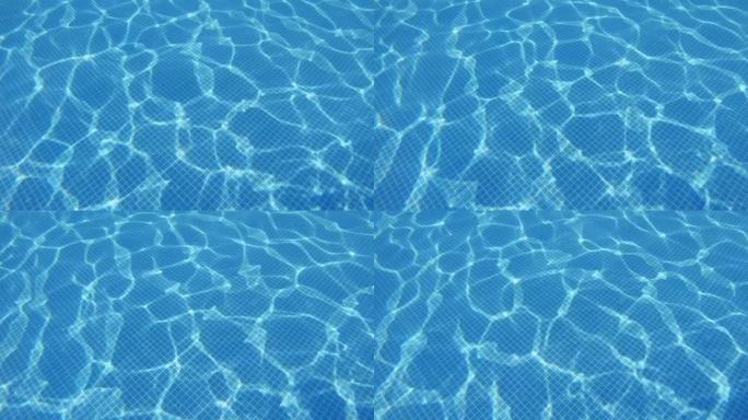 清澈蓝色泳池水的反射，闪烁。晴天平静休息。水池中明亮的绿松石水面的质地。泳池水背景，白天日落时波浪形