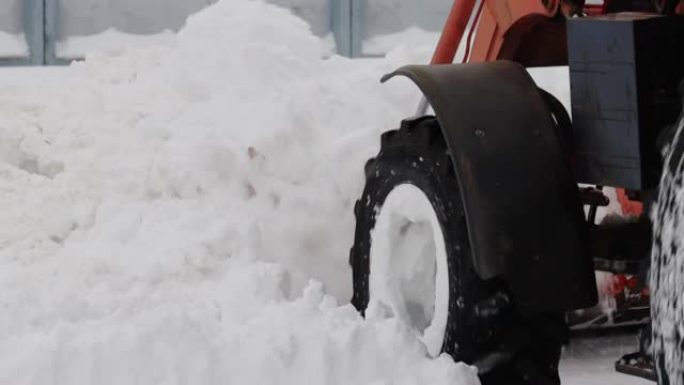 带有黄色桶的拖拉机在冬天从街上除雪。道路清洁援助。慢动作