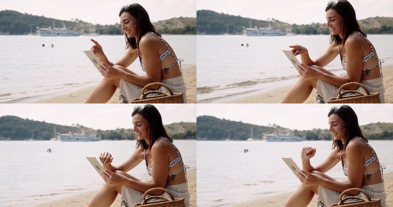 白种人快乐的女性在海滩上放松，在数字平板电脑上的海洋阅读书籍