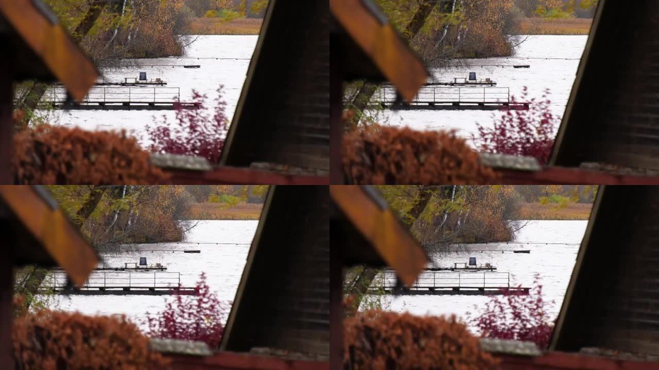 湖上的长墩，透过房屋的木制屋顶可以看到。红、黄、金树在风中摇曳