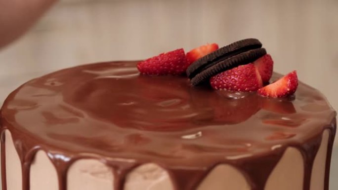 女人糖果用浆果和饼干装饰巧克力蛋糕，特写镜头。慢动作。蛋糕制作过程
