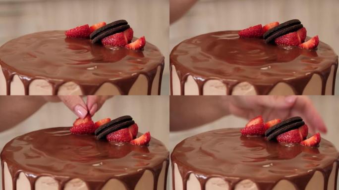 女人糖果用浆果和饼干装饰巧克力蛋糕，特写镜头。慢动作。蛋糕制作过程