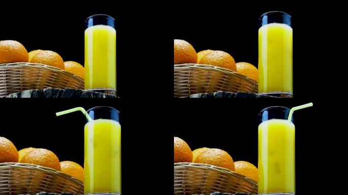 黄色柠檬水，稻草和新鲜的天然橙子放在黑色背景的篮子里。夏季水果冰镇冰饮料