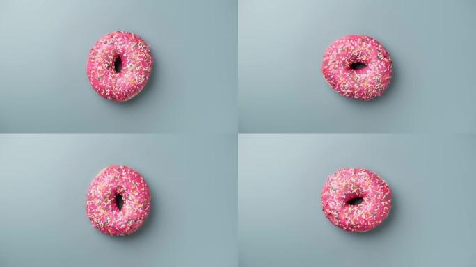 浅蓝色背景下的粉红色糖霜甜甜圈。甜点。