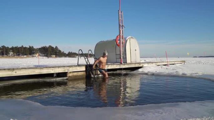 一个男人在冬天的冰洞里游泳