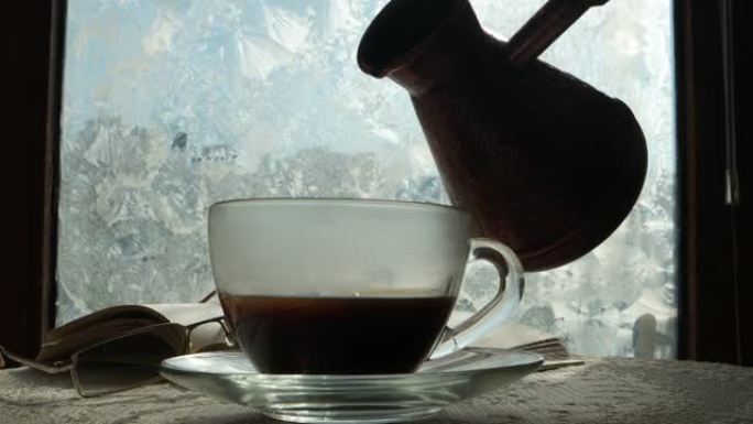 一杯咖啡和一本打开的书在冬天霜冻的窗台上
